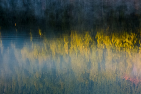 beautiful abstract nature background of lake surface reflecting spruce forest textures in morning...