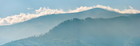 panoramic view of clouds rising behind the blue mountain. wonderful morning backgroundの写真素材