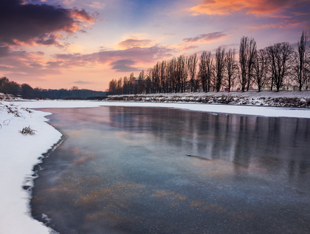 beautiful sunset on the frozen river. location Nealezhnosti embankment in Uzhgorod. beginning of the longest European linden alley in winterの写真素材