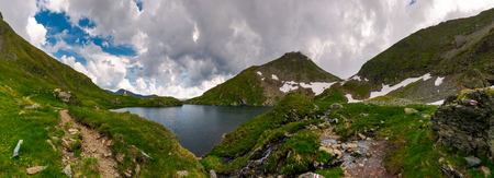 panorama of Capra lake, Romania. gorgeous landscape of Fagarasan mountains on a cloudy summer dayの写真素材