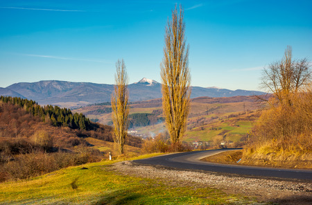 new asphalt road in to the mountains. Pikui mountain with snowy top in the distance. beautiful sunny weather in late autumn. location Volovets serpentine, TransCarpathia, Ukraineの写真素材