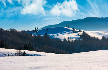 mountainous landscape on a bright winter day. wonderful cloudscape above the snow covered hills rolling hillsの写真素材