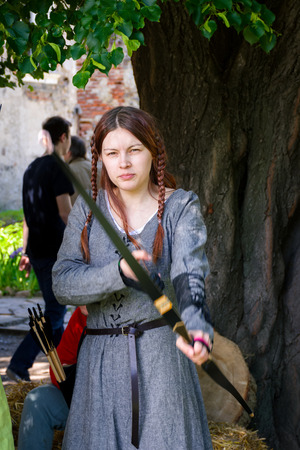 Chynadiyovo, Ukraine - May 27, 2017: medieval culture festival Silver Tatosh. Location St. Miklos Castle. Archer girl pulling the string and aiming at youのeditorial素材
