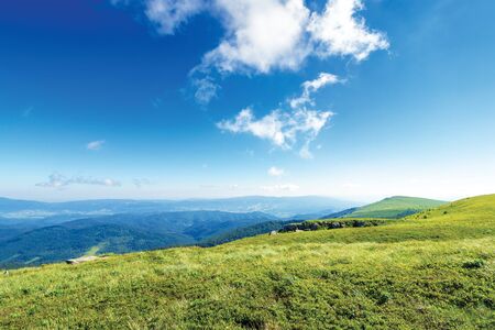 beautiful summer landscape in mountains. grassy meadows, rocks and summit in the distance. interesting cloud formation on the blue sky. ridge in the distanceの写真素材