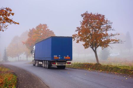 transcarpathia, ukraine - oct 09, 2018: truck on the serpentine in fog. breaking before the road turn. trees in fall foliage. sneaky autumn weather. deceptive nature beauty concept.のeditorial素材