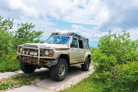 mnt. Runa, Ukraine - JUN 19, 2019: old off road vehicle on the paved mountain road. dirty SUV prepared for the battle with nature. mountain in the distance beneath a cloudy skyのeditorial素材
