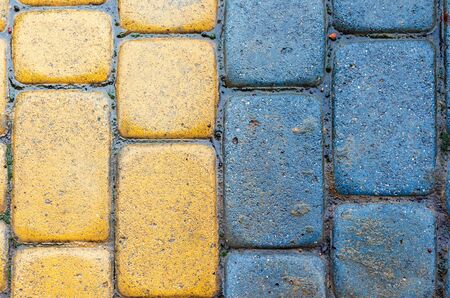 yellow and blue cobbles of pavement texture. stone masonry floor covering close up. top view of vertical wet grungy backgroundの写真素材