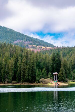 lake among the coniferous forest in mountains. beautiful nature scenery of synevyr national park in dappled light.の写真素材