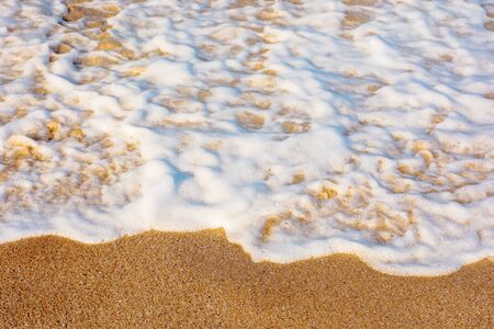 sea waves splash foam on the sunny beach.  mess of salt water and sand in evening light. dynamic...