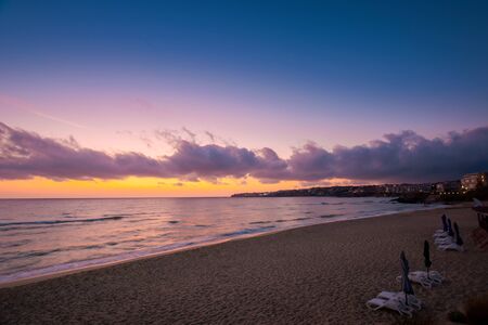 dawn at the beach of a black sea. gorgeous sky above the water surface. tide washing the shoreの写真素材