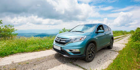 mnt. runa, ukraine - JUN 22, 2019: cyan honda cr-v suv on the mountain road. explore the wilderness concept. ridge in the distance. sunny weather. clouds on the blue skyのeditorial素材