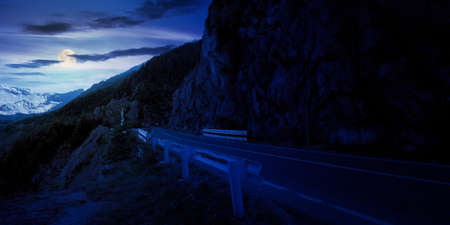 mountain road in fagaras ridge at night. popular travel destination in full moon light. wide serpentine. summer morning sceneryの写真素材