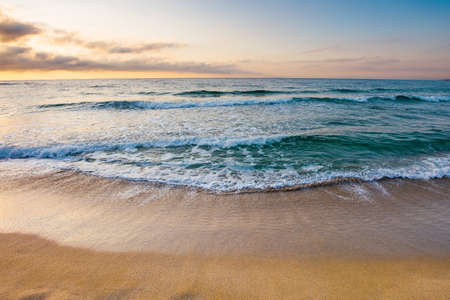 sunrise at the sea. beautiful summer landscape on the sandy beach. green waves rush on the shore in...