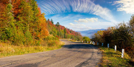 old serpentine road in mountains. beautiful autumn scenery on a sunny day. trees in colorful...