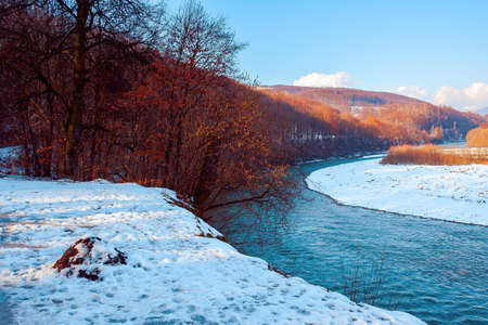 river in the winter scenery. mountain landscape on the sunny day. trees on the snow covered river...