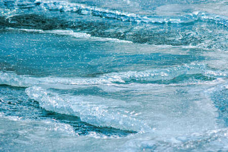ice texture on the river. close up background. blue color in day light. water flow among cracks
