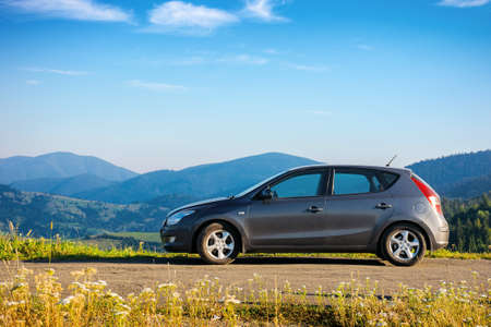 car on the concrete parking on top of the mountain in morning light. travel countryside concept. beautiful nature scenery views in summer with fluffy clouds on the blue skyの写真素材