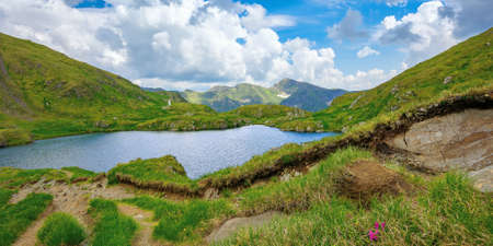 summer landscape with lake on high altitude. beautiful scenery of fagaras mountain ridge in summer. open view in to the distant peak beneath a fluffy clouds. Capra lacul, Romaniaの写真素材
