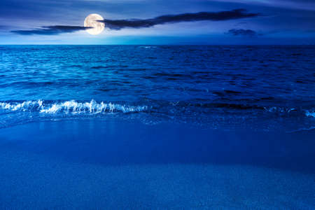 calm morning scenery at the sea. empty sandy beach in full moon light. relax and summer vacation concept. clouds on the sky at nightの写真素材