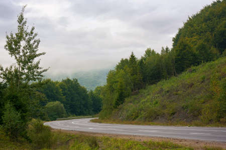 asphalt road through mountains on a cloudy day. wonderful rural landscape in early autumn