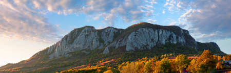 rocky formation in apuseni mountains at sunset. gorgeous autumn landscape in evening light. trees on the hills in colorful foliage. location masivul-vulcan, hunedoara country of romaniaの写真素材