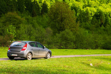 turya, ukraine - MAY 17, 2021: small hatchback in outdoor nature scenery. car on the countryside road through meadow. trees on the near by hill. beautiful springtime landscape in morning lightのeditorial素材