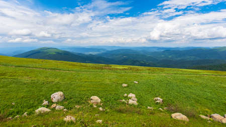 green summer landscape in mountains. outdoor scenery with blue sky and clouds. beautiful nature backgroun on a sunny day. stones on the grassy hillの写真素材