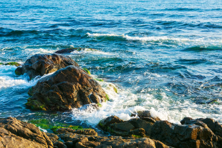 rocky coast in morning light. sea waves crashing over rocks. black sea scenery in summerの写真素材