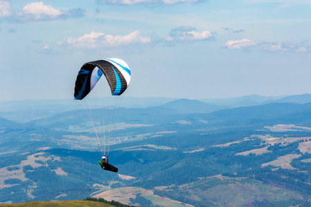 paragliding above the mountain valley. extreme outdoor sports. adventure and travel concept. clouds on the sky in summerの写真素材