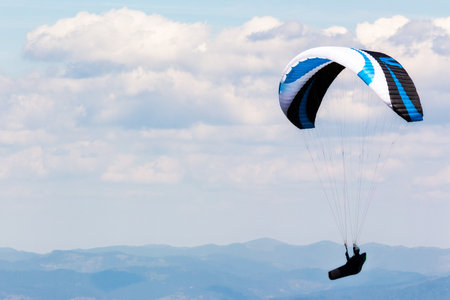 paragliding above the mountain valley. extreme outdoor sports. adventure and travel concept. clouds on the sky in summerの写真素材