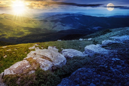 landscape with white sharp boulders on the hillside near mountain peak with sun and moon at twilight. day and night time change concept. mysterious countryside scenery in morning lightの写真素材