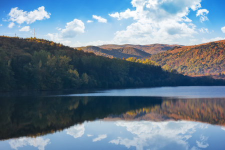 mountainous autumn landscape with lake. nature background with trees on the shore reflecting in the...