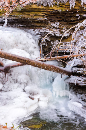 frozen waterfall scenery in winter. ice covered water stream among bouldersの写真素材
