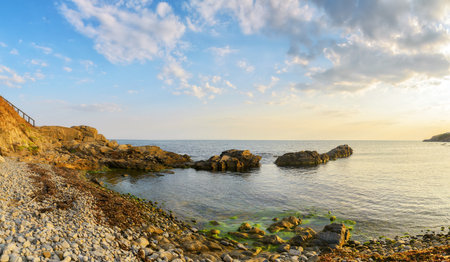 pebble sea shore of bulgaria with rocks at sunrise. beautiful outdoor scenery with view in to the...
