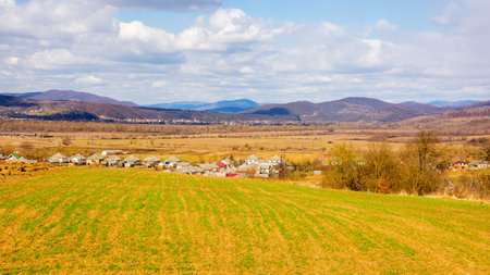 village in the wide valley in spring. mountainous rural landscape of ukraine. agricultural fields on the hills. clouds on the sky. wonderful countryside scenery of transcarpathiaの写真素材