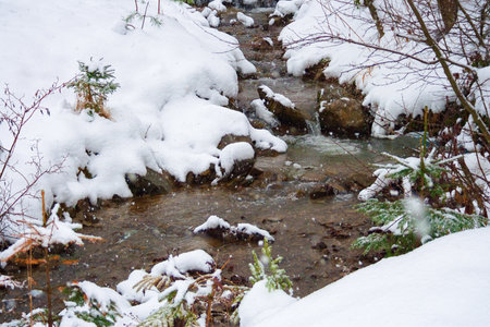 small creek in winter. cold water. snow covered shore. snowy weatherの写真素材