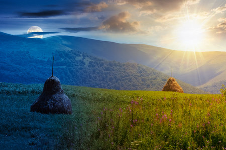 rural mountain landscape on summer solstice. day and night time change concept. haystack on green hill. alpine scenery at the foot ridge with sun and moon at twilightの写真素材
