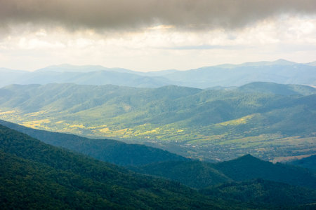 mountain landscape with green peak under storm sky. beautiful summer scenery of carpathian watershed ridge. scenic view of valley in dappled light. outdoor adventure in highland of ulraineの写真素材