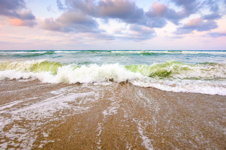 sea tide before storm. wave splash with foam on wet sandy beach. windy weather on velvet season. dramatic seascape backgroundの写真素材