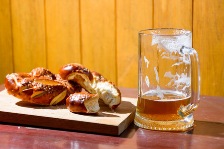 beer and pretzel on the table. celebration of oktoberfest. glass mug with cold beverage and baked...