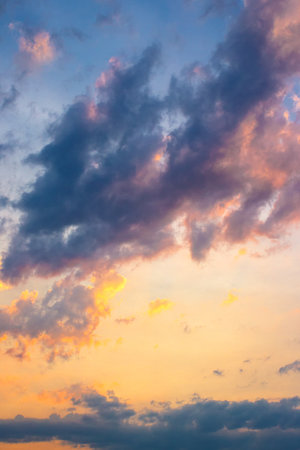 dark cloudscape at sunset. orange-purple clouds on a yellow-blue gradient of sky in evening light....