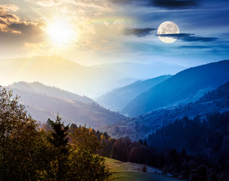 beautiful afternoon in carpathian mountains. day and night time change concept. scenic autumn equinox weather. forest in colorful foliage. distant valley in haze with sun and moon at twilightの写真素材