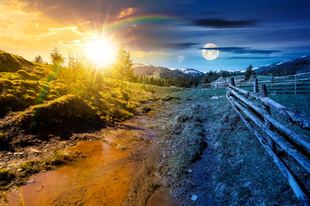rural scene of mountain landscape on spring equinox. day and night time change concept. green countryside with forested hills with sun and moon at twilightの写真素材