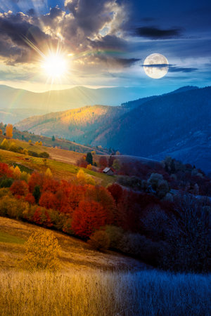 mountain landscape of countryside on autumn equinox. day and night time change concept. beautiful view of range with dappled light on forested slopes in colorful foliage with sun and moon at twilightの写真素材