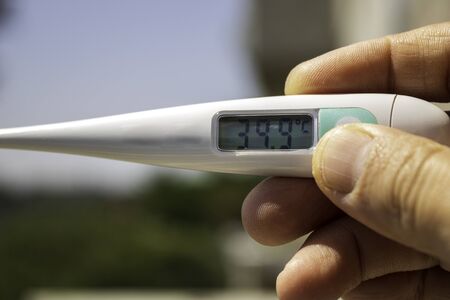 Person holding a thermometer on his balcony