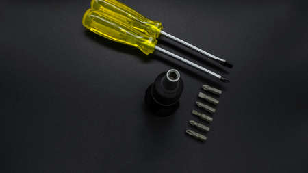 Yellow screwdriver and small multi-bit screwdriver on a black backgroundの写真素材