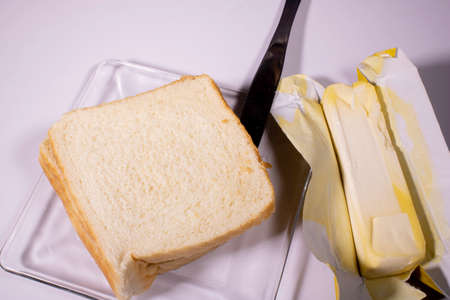White box bread in glass dish with butter on the side, about to be spread