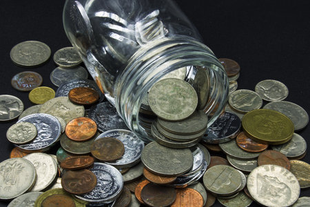 Piggy bank that was opened to be able to get the savings money from a glass jar, with old coins on a black backgroundの写真素材