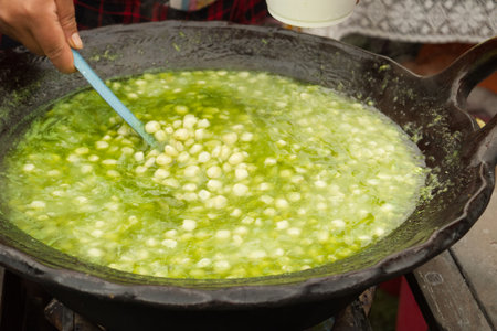 Person preparing esquites in a clay pot, with epazote seasoningの写真素材