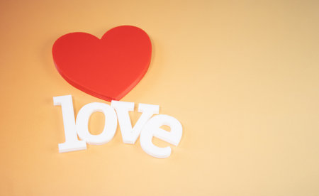 Red heart and love word on orange background. Valentine's day concept.の写真素材